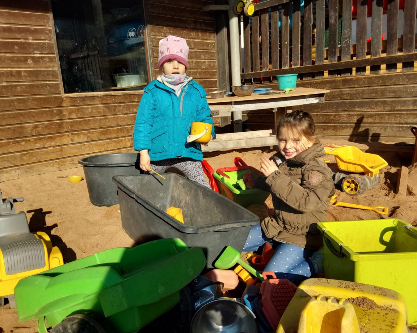 Kinder spielen im Sand und lächeln in die Kamera