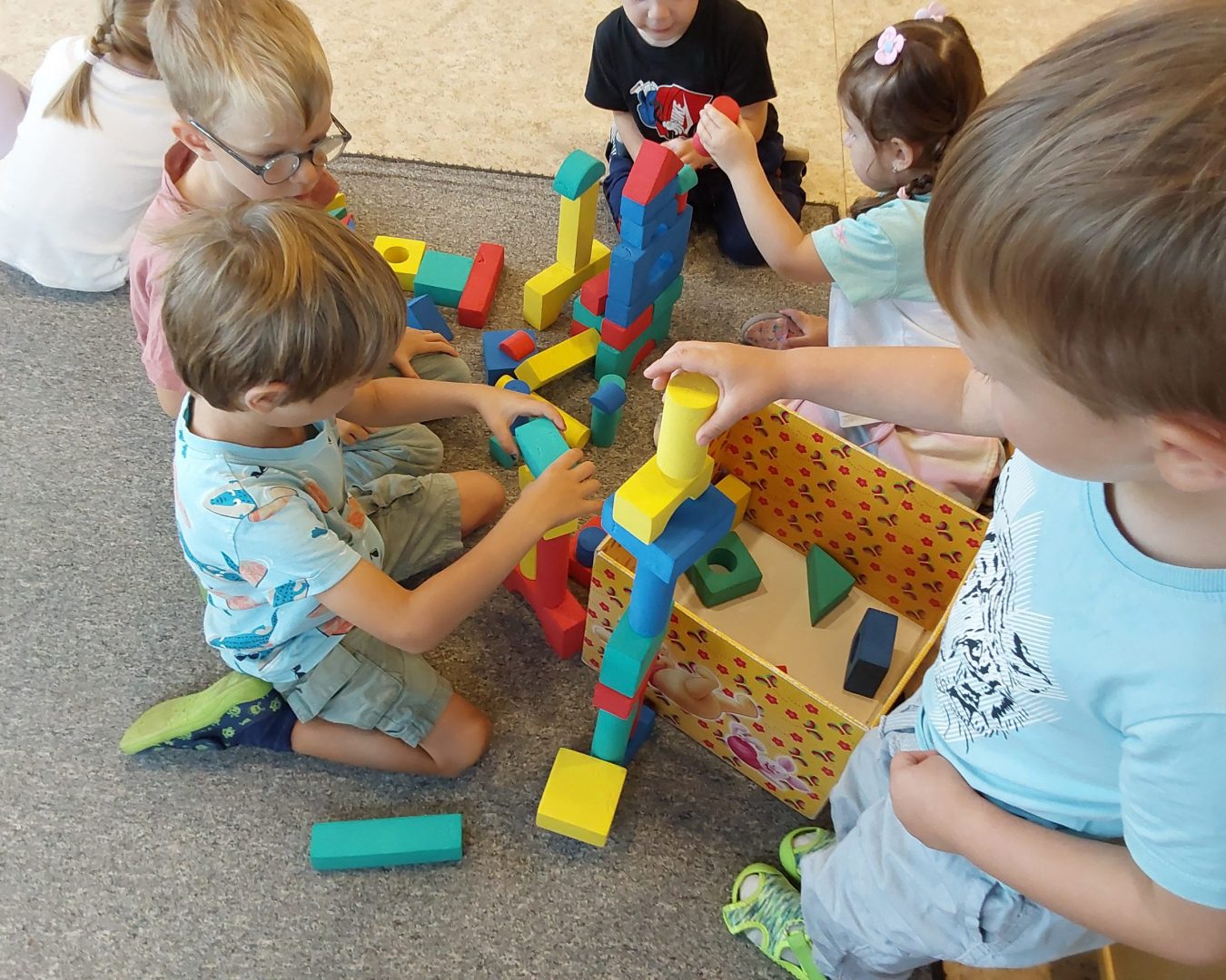 Kindergartenkinder bauen mit kleinen bunten Bauklötzen Türme.